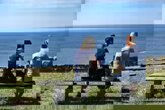 couple sitting on bench near sea during daytime